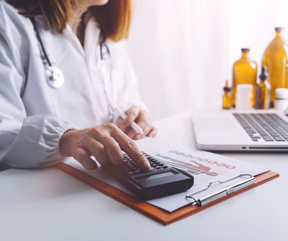 Ärztin mit Taschenrechner, Klemmboard und Laptop